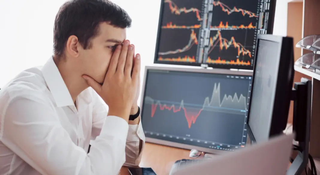 aggódó befektető eső grafikonokat néz monitoron